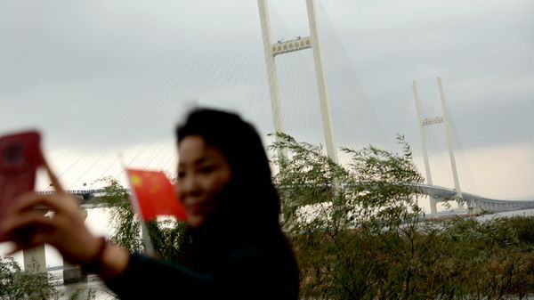 Женщина позирует с китайским флагом перед недавно открытым мостом через реку Ялуцзян - Sputnik Србија