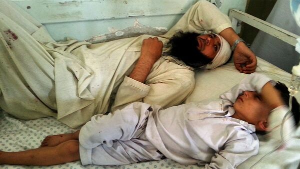 Avganistanac i dete leže na krevetu nakon što su ranjeni u eksploziji u provinciji Kunar, Avganistan, u nedelju, septembar 20, 2015. - Sputnik Srbija