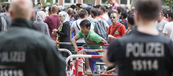 Полиција стоји поред азиланата који чекају испред прихватног центра за избеглице у Берлину, Немачка, петак, 7. августа, 2015. Полиција стоји поред азиланата који чекају испред прихватног центра за избеглице у Берлину, Немачка, петак, 7. августа, 2015. - Sputnik Србија