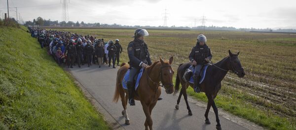 Policajci voze na konjima idu ispred migranata nakon što su prešli iz Hrvatske, u Dobova, u blizini graničnog prelaza između Hrvatske i Slovenije u utorak, 20. oktobra, 2015. godine. - Sputnik Srbija