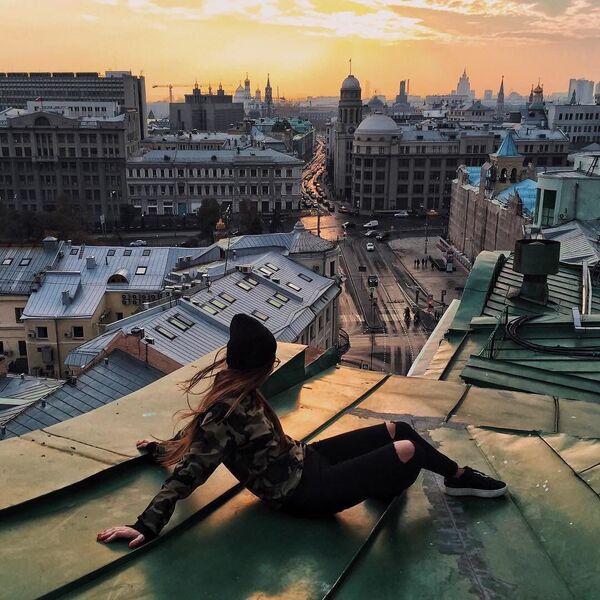 Девојка посматра залазак сунца на једном од кровова у близини станице метроа Китај-города - Sputnik Србија