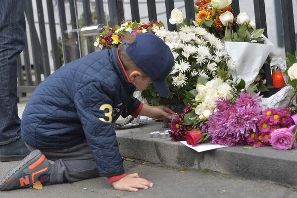 Dečak pali sveću ispred francuske ambasade u Beogradu. - Sputnik Srbija