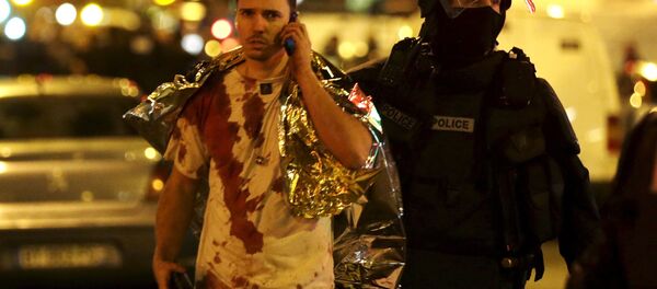 Француски полицајац помаже једној од жртава која је умазана крвљу у близини позоришта Батаклан, Париз Француски полицајац помаже једној од жртава која је умазана крвљу у близини позоришта Батаклан, Париз - Sputnik Србија