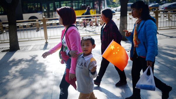 Žena sa detetom koje nosi zastavu Kine u Pekingu - Sputnik Srbija