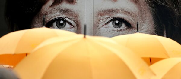 Supporters of the Christian Democratic Union (CDU) hold umbrellas in front of a giant portrait of German Chancellor Angela Merkel during an election campaign event in front of the party's headquarter in Berlin, Germany, Monday, Sept. 16, 2013. - Sputnik Srbija