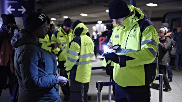 Полицајац проверава пасош путнице на железничкој станици међународног аеродрома у Копенхагену, Данска, да би спречио улаз избеглица у Шведску. - Sputnik Србија