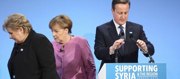 Britanski premijer Dejvid Kamerun za govornicom a iza njega je nemačka kancelarka Angela Merkel - Sputnik Srbija