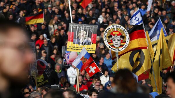 Демонстарнти у Дрездену носе транспаренте против канцеларке Ангеле Меркел - Sputnik Србија