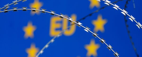 Бодљикава жица се види испред заставе Европске уније (ЕУ) - Sputnik Србија
