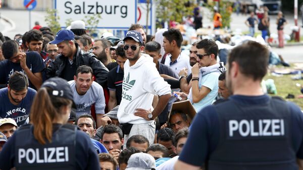 Nemački policajci stoje ispred migranata koji čekaju da pređu granicu iz Austrije u Nemačku, Nemačka - Sputnik Srbija