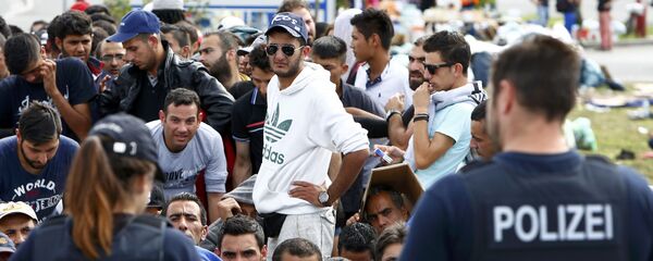 Nemački policajci stoje ispred migranata koji čekaju da pređu granicu iz Austrije u Nemačku, Nemačka Nemački policajci stoje ispred migranata koji čekaju da pređu granicu iz Austrije u Nemačku, Nemačka - Sputnik Srbija