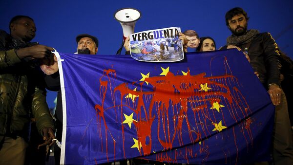 Демонстранти држе заставу Европске уније умрљану фарбом и учествују у протесту против европске политике за избеглице у Мадриду 11. март 2016. године - Sputnik Србија