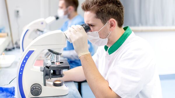 Naučnici i forenzički analitičari rade za mikroskopom u laboratoriji - Sputnik Srbija