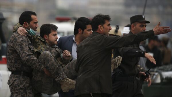 Avganistanske snage bezbednosti nose povređenog pripadnika obezbeđenja nakon eksplozije automobila-bombe u Kabulu - Sputnik Srbija