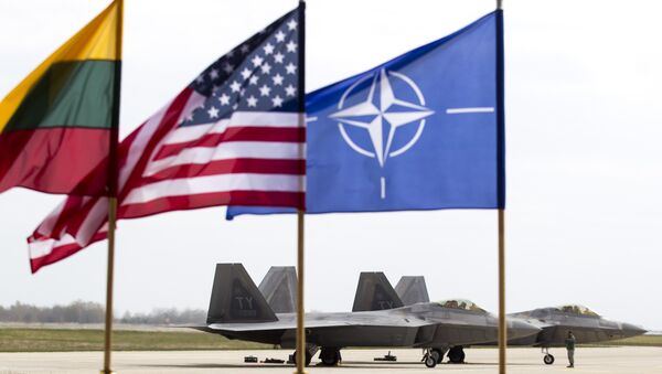 Američki F-22 Raptor borbeni avioni stoje na pisti u vazduhoplovnoj bazi u Litvaniji, pored zastava Litvanije , NATO i SAD - Sputnik Srbija