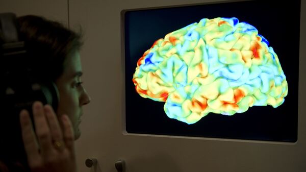 Žena posmatra funkcionalnu sliku magnetne rezonance koji pokazuje delove ljudskog mozga - Sputnik Srbija