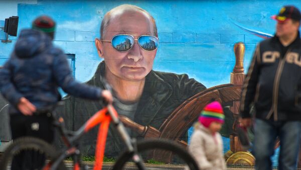 Pešaci prolaze pored portreta ruskog predsednika Vladimira Putina na zidu u Jalti - Sputnik Srbija