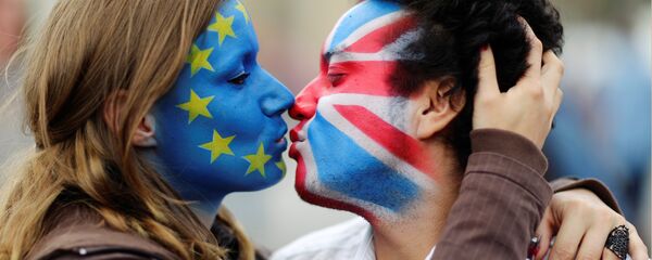 Dvoje aktivista ofarbanih lica bojama zastave EU i Velike Britanije ljube se ispred Branderbuške kapije u Berlinu. - Sputnik Srbija