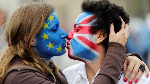 Dvoje aktivista ofarbanih lica bojama zastave EU i Velike Britanije ljube se ispred Branderbuške kapije u Berlinu. - Sputnik Srbija