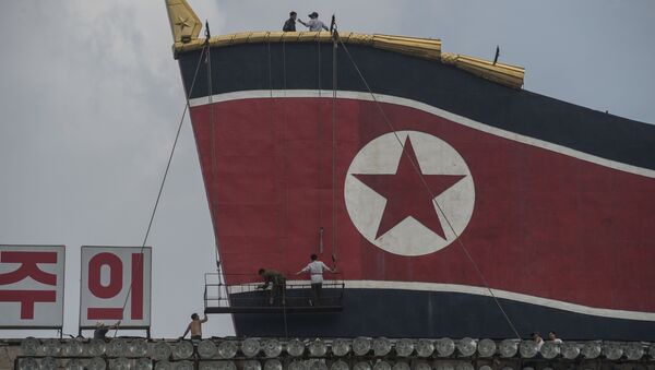 Radnici slikaju zastavu Severne Koreje na zgradi na Trgu Kim Il Sunga. - Sputnik Srbija