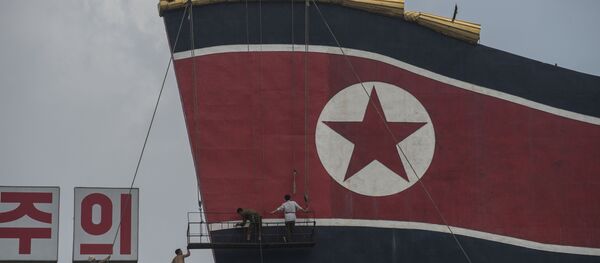 Радници сликају заставу Северне Кореје на згради на Тргу Ким Ил Сунга. - Sputnik Србија