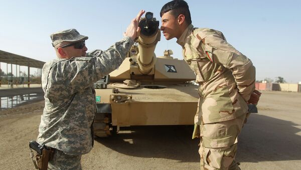 Američki vojni trener pokazuje iračkom vojniku kako se koristi kolimator za kalibraciju cevi jednog od tenkova „Abrams” tokom treninga u osnovi kompleksu Taji, gde se nalaze iračke i američke trupe. - Sputnik Srbija