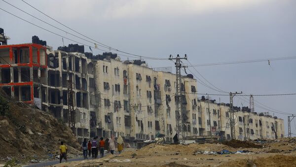 Palestinci se kreću pored uništenih zgrada u pojasu Gaze. - Sputnik Srbija