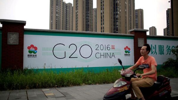 Čovek na motociklu prolazi pored bilborda za samit G20 u kineskom gradu Hangžu - Sputnik Srbija