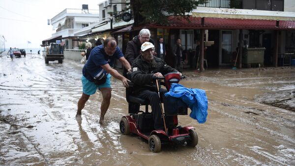 Људи се пробијају кроз поплављену улицу у селу Аја Тријада 20 километара од Солуна. - Sputnik Србија