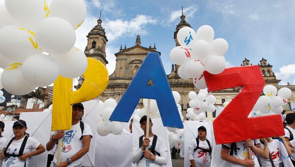 Ljudi stoje sa natpisom Mir na Bolivarovom trgu ispred katedrale u Bogoti, Kolumbija. - Sputnik Srbija