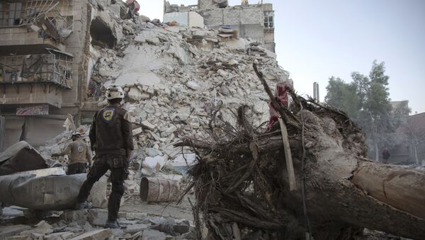 Члан Сиријске цивилне заштите, познате и као Бели шлемови, стоји поред порушених зграда у Алепу - Sputnik Србија