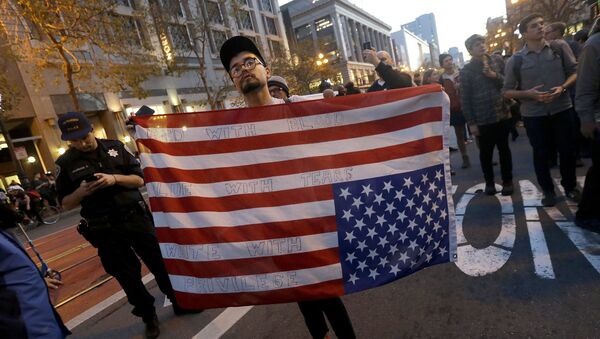 Demonstrant nosi američku zastavu naopačke tokom protesta protiv Trampa u San Francisku - Sputnik Srbija