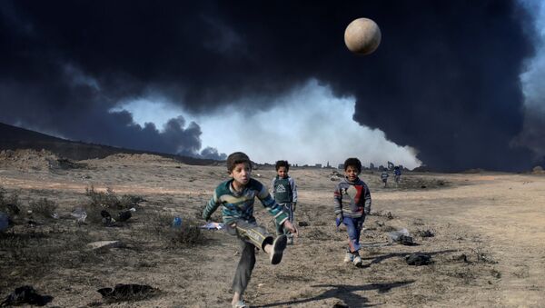 Деца играју фудбал у близини нафтних поља које је спалио ДАЕШ, јужно од Мосула - Sputnik Србија