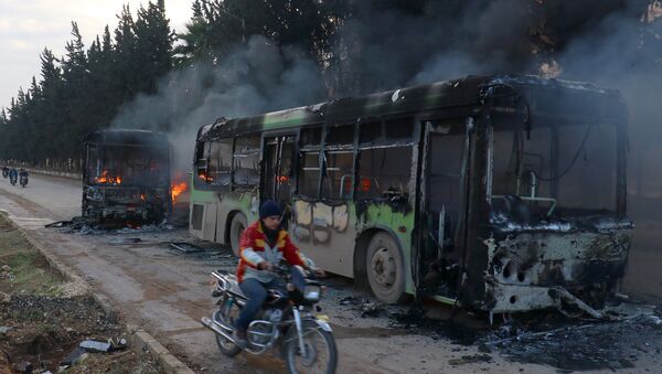 Motociklista prolazi pored zapaljenog autobusa na putu ka opkoljenim sirijskim naseljima Fua i Kefraja - Sputnik Srbija