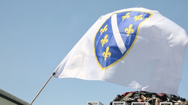 Zastava Bosne i Hercegovine ispred gomile cipela i logoa UN ispred Brandenburške kapije u Berlinu. - Sputnik Srbija