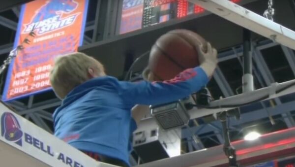 Дечак скида лопту заглављену у обручу коша на кошаркашкој утакмици - Sputnik Србија