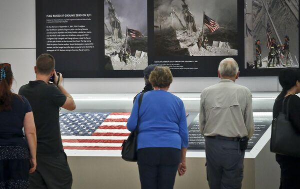 Visitors view the display for the American flag, left, that firefighters hoisted at ground zero in the hours after the 9/11 terror attack  at the Sept. 11 museum in New York - Sputnik Srbija