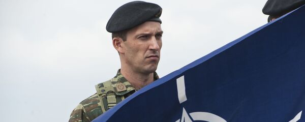 Припадник КФОРА  Приштини поред НАТО заставе - Sputnik Србија