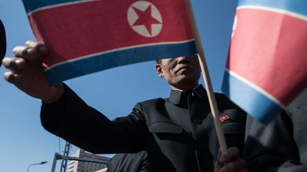 Становник носи заставу Северне Кореје на свечаности отварања новог стамбеног комплекса у Пјонгјангу - Sputnik Србија