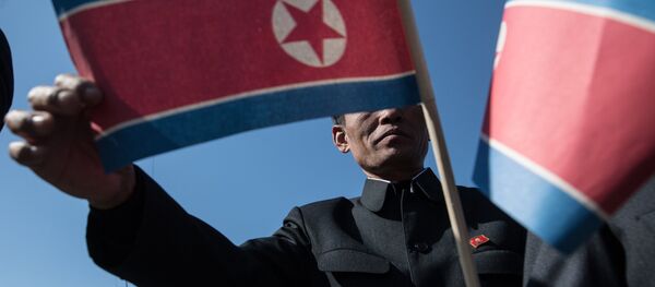 Становник носи заставу Северне Кореје на свечаности отварања новог стамбеног комплекса у Пјонгјангу - Sputnik Србија