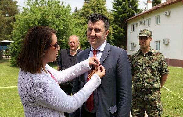 Новинарка Спутњика Сенка Милош ставља Георгијевску ленту министру обране Зорану Ђорђевићу. Новинарка Спутњика Сенка Милош ставља Георгијевску ленту министру обране Зорану Ђорђевићу. - Sputnik Србија