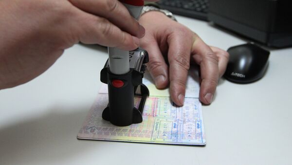 Pripadnik beloruske pogranične službe stavlja pečat u pasoš na belorusko-poljskoj granici - Sputnik Srbija