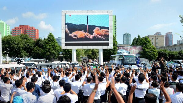 Ljudi gledaju na ekranu probu ispaljivanja rakete u Pjongjangu, Severna Korea. - Sputnik Srbija