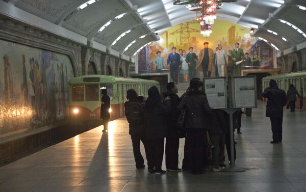 Putnici severnokorejskih metroa okupljaju se oko javnog štanda na platformi vozova u Pjongjangu - Sputnik Srbija