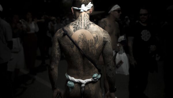 На фотографији снимљеној 20. маја 2017. године, мушкарац позира показујући свој “Ирезуми”, јапанску традиционалну тетоважу која се односи на Јакуза универзум, за време Сања Мацурти фестивала у Токију. - Sputnik Србија