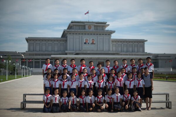 Đaci iz Severne Koreje poziraju ispred portreta pokojnih lidera Kim Il Sunga i Kim Džong Ila.  - Sputnik Srbija