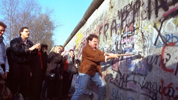 An unidentified West Berliner swings a sledgehammer, trying to destroy the Berlin Wall near Potsdamer Platz, on November 12, 1989, where a new passage was opened nearby - Sputnik Srbija