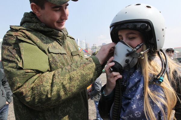 Vojnik pomaže devojci da stavi pilotsku kacigu na Sajmu vojne tehnike u Vladivostoku - Sputnik Srbija