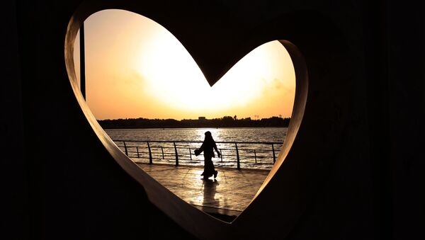 Saudi woman seen through a heart-shaped statue walks along an inlet of the Red Sea in Jiddah, Saudi Arabia - Sputnik Srbija