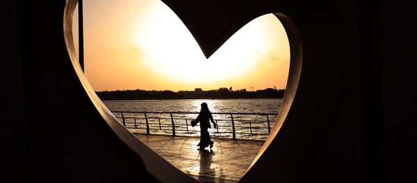 Saudi woman seen through a heart-shaped statue walks along an inlet of the Red Sea in Jiddah, Saudi Arabia - Sputnik Srbija